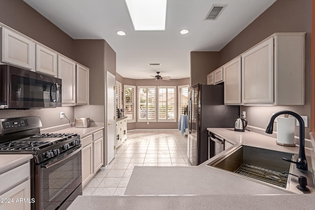 kitchen featuring appliances with stainless steel finishes, ceiling fan, sink, light tile patterned floors, and white cabinetry