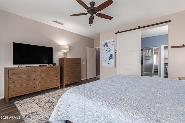 bedroom with a barn door, dark hardwood / wood-style floors, and ceiling fan