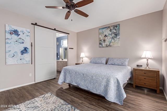 bedroom featuring a barn door, ensuite bath, ceiling fan, and dark wood-type flooring