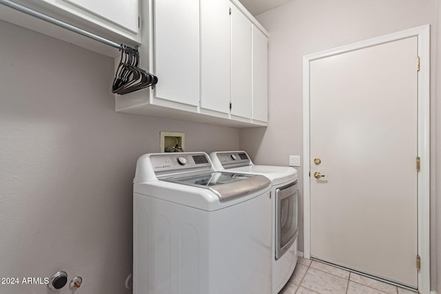 washroom with cabinets, light tile patterned floors, and washing machine and clothes dryer