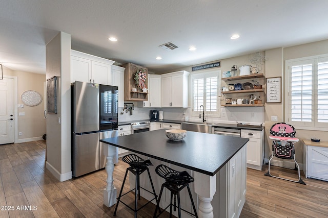 12238 W Patrick Ct, Sun City, AZ 85373 - kitchen featuring open shelves, stainless steel appliances, a sink, dark countertops, and white cabinets
