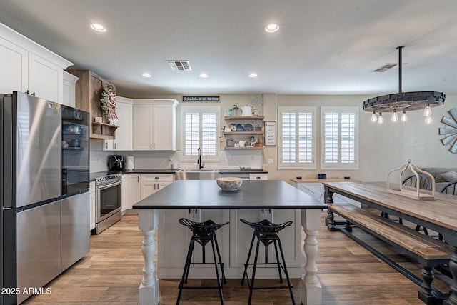 12238 W Patrick Ct, Sun City, AZ 85373 - kitchen with open shelves, stainless steel appliances, a sink, dark countertops, and white cabinetry