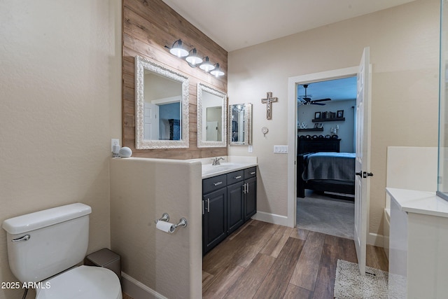 12238 W Patrick Ct, Sun City, AZ 85373 - bathroom featuring wood finished floors, toilet, connected bathroom, vanity, and baseboards