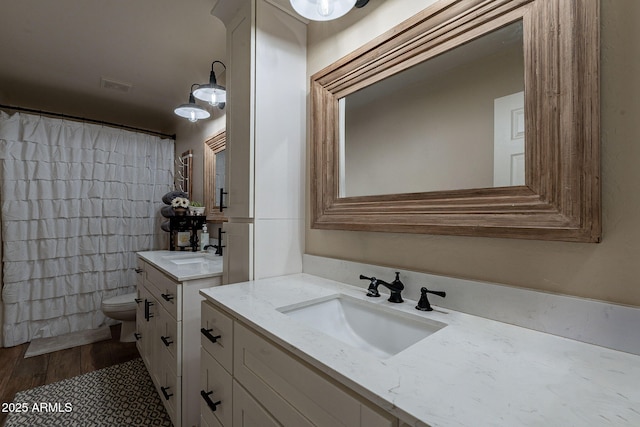 12238 W Patrick Ct, Sun City, AZ 85373 - bathroom featuring toilet, two vanities, a shower with curtain, and wood finished floors