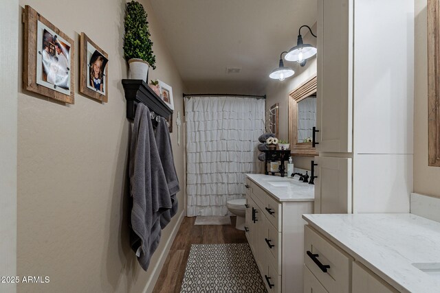 12238 W Patrick Ct, Sun City, AZ 85373 - full bathroom with wood finished floors, toilet, two vanities, and curtained shower