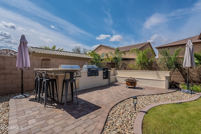 12238 W Patrick Ct, Sun City, AZ 85373 - view of patio / terrace featuring an outdoor bar, a fire pit, area for grilling, grilling area, and a fenced backyard