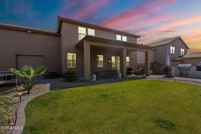 12238 W Patrick Ct, Sun City, AZ 85373 - rear view of property with an outdoor kitchen, stucco siding, a garage, a patio area, and outdoor lounge area