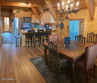 403 W Sherwood Dr, Payson, AZ 85541 - dining space with vaulted ceiling with beams, light wood-style floors, a chandelier, and wooden walls