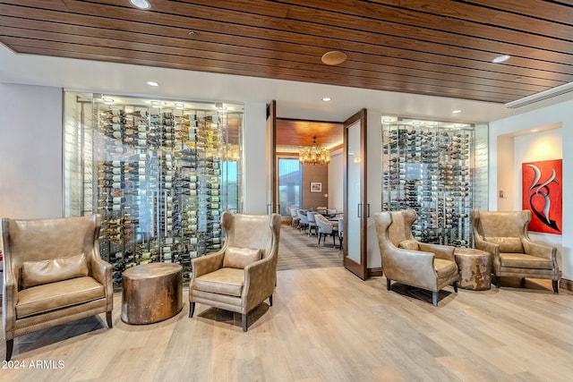 living area featuring light hardwood / wood-style flooring, wooden ceiling, and a notable chandelier