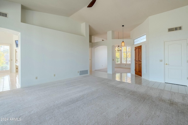 carpeted spare room with ceiling fan and high vaulted ceiling