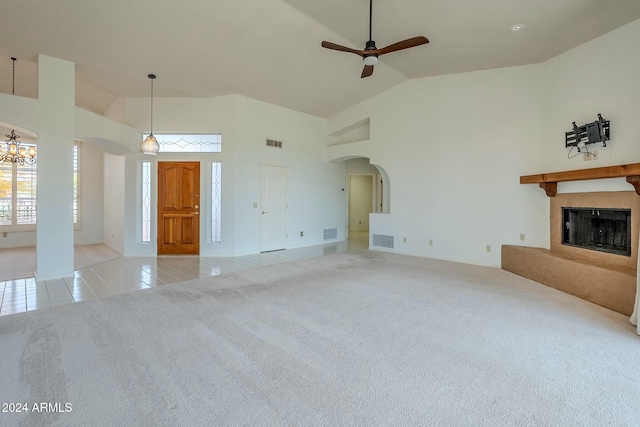 unfurnished living room with ceiling fan with notable chandelier, high vaulted ceiling, and light tile patterned flooring