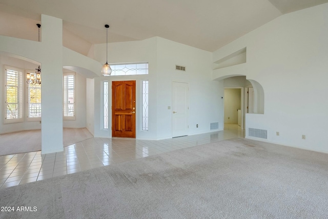 tiled empty room featuring a notable chandelier and high vaulted ceiling