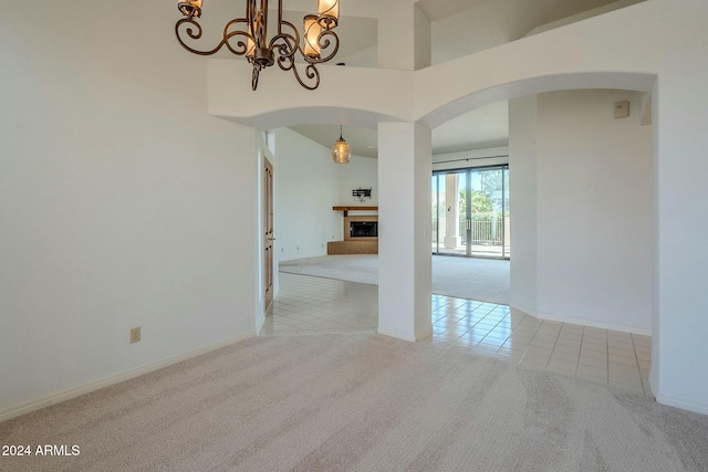 carpeted spare room with a towering ceiling and an inviting chandelier