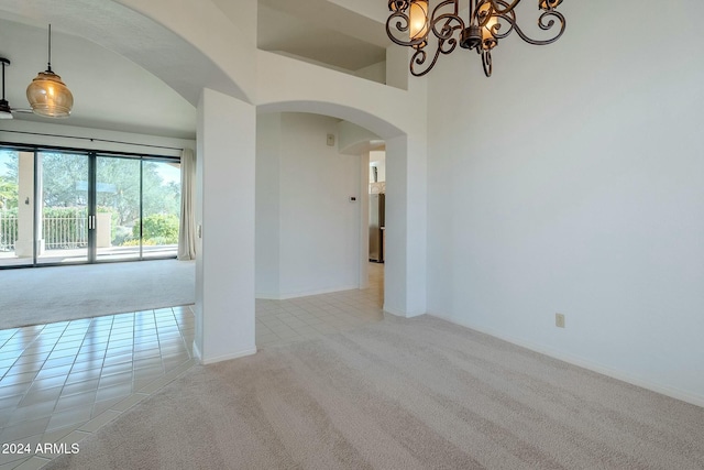 spare room featuring light colored carpet and an inviting chandelier