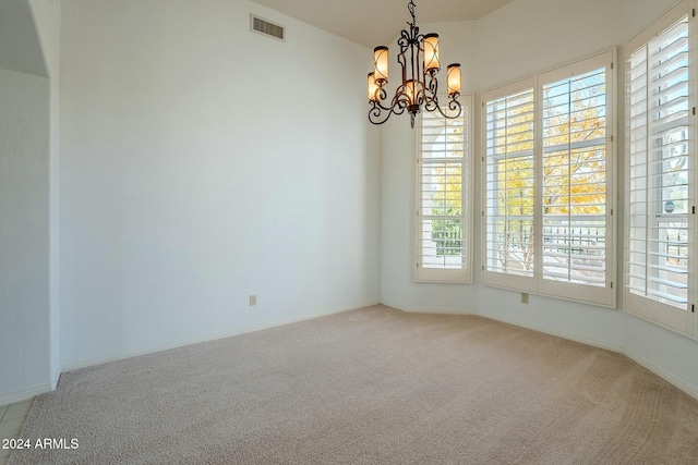 carpeted empty room featuring a chandelier