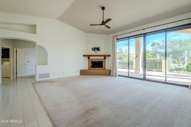 unfurnished living room featuring washer and dryer, ceiling fan, light tile patterned floors, and lofted ceiling