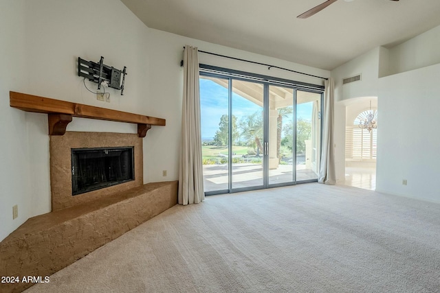 unfurnished living room with ceiling fan with notable chandelier, carpet floors, lofted ceiling, and a premium fireplace