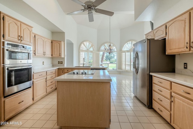 kitchen featuring a center island, sink, appliances with stainless steel finishes, light brown cabinetry, and light tile patterned flooring