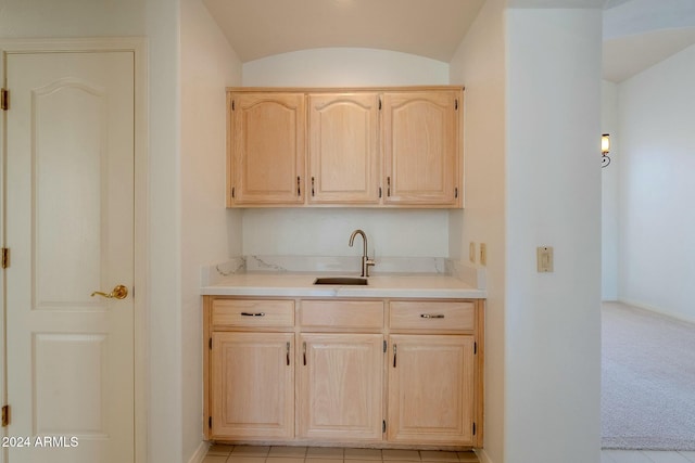 bar with light brown cabinets, light tile patterned floors, lofted ceiling, and sink