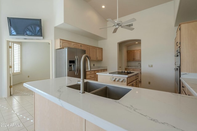 kitchen with light brown cabinets, high vaulted ceiling, sink, light tile patterned floors, and stainless steel appliances