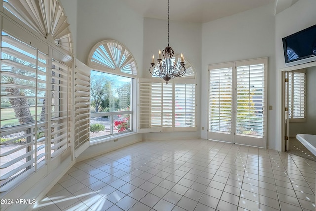 unfurnished dining area featuring light tile patterned floors, a chandelier, and high vaulted ceiling