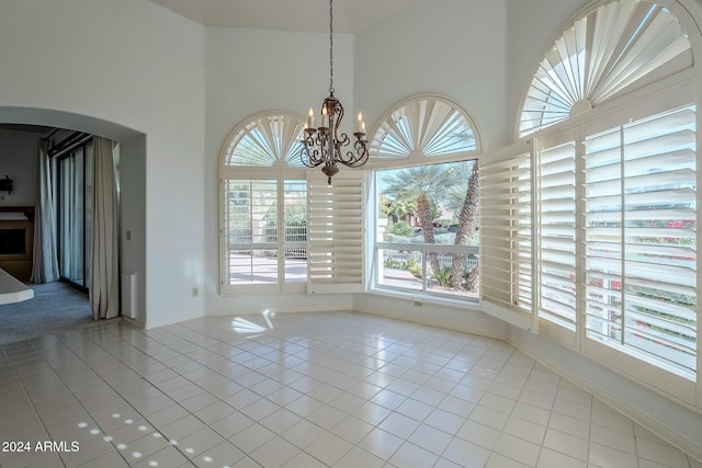 unfurnished dining area featuring light tile patterned floors and a notable chandelier