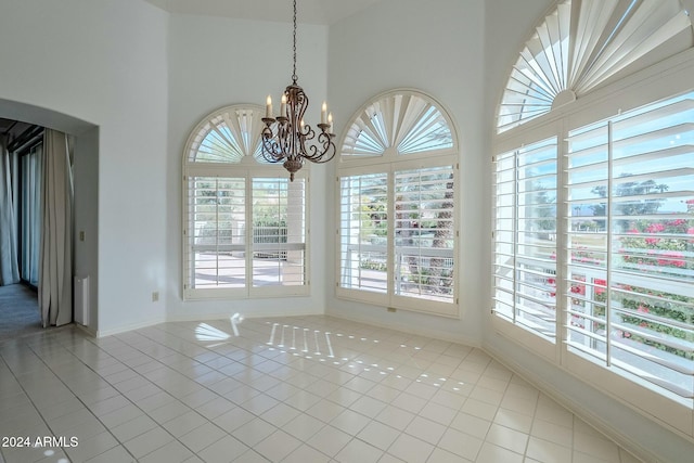 unfurnished dining area featuring light tile patterned flooring, a wealth of natural light, and a chandelier