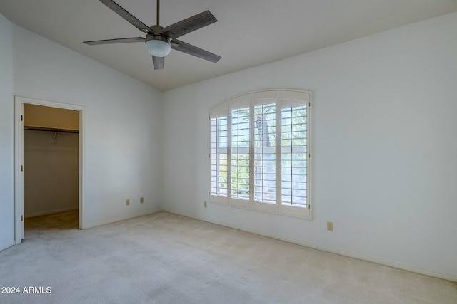 unfurnished bedroom featuring light carpet, a spacious closet, multiple windows, and ceiling fan