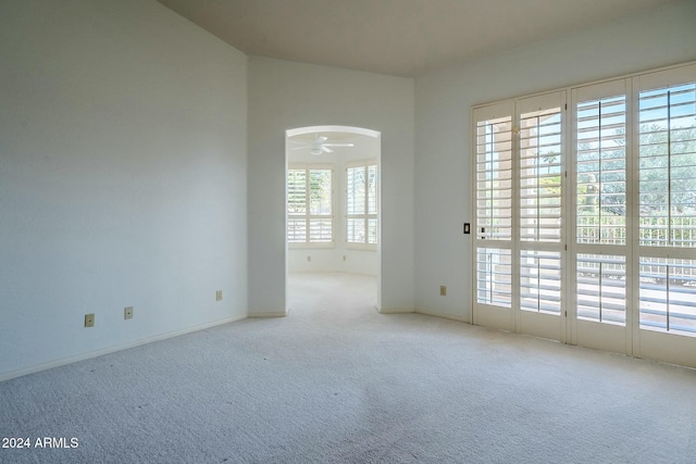 carpeted empty room with a wealth of natural light and ceiling fan