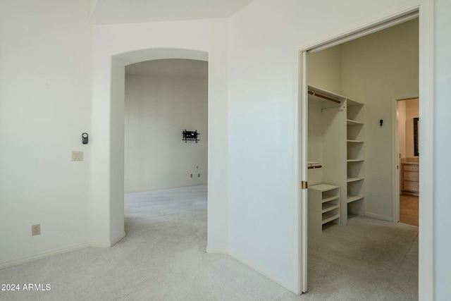 hall with built in shelves and light colored carpet