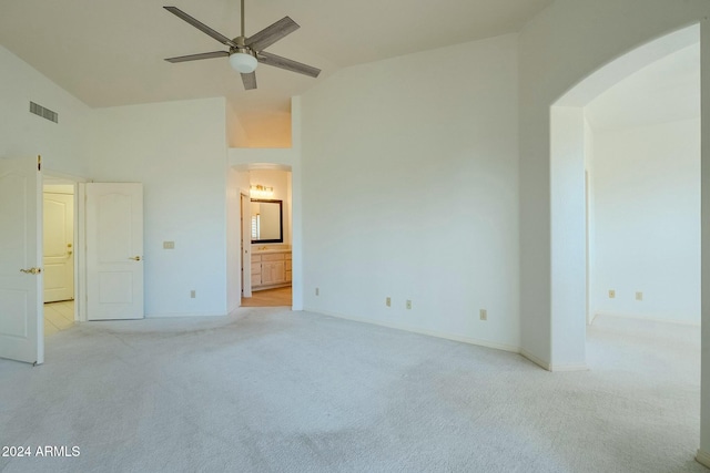 unfurnished bedroom featuring ensuite bathroom, ceiling fan, light carpet, and high vaulted ceiling