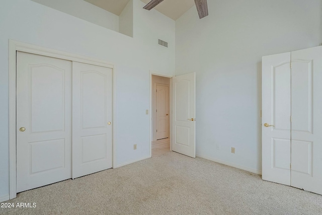 unfurnished bedroom with light carpet, a closet, high vaulted ceiling, and ceiling fan