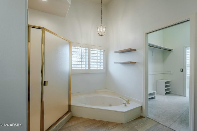 bathroom featuring hardwood / wood-style flooring, an inviting chandelier, and independent shower and bath