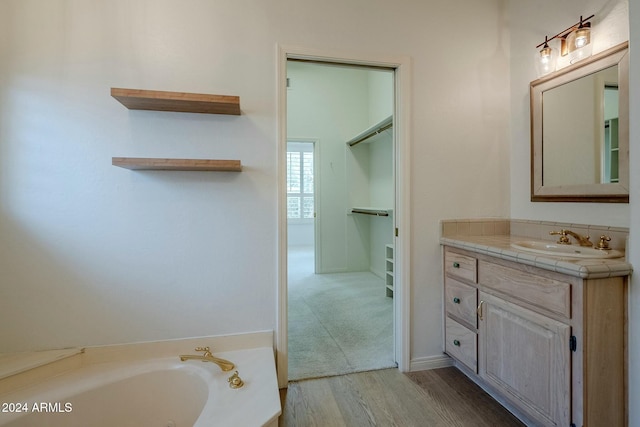 bathroom featuring vanity, wood-type flooring, and a tub to relax in