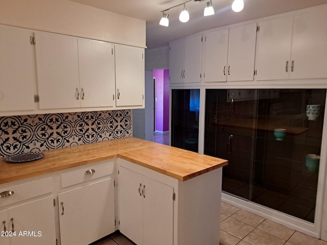 kitchen featuring white cabinets, butcher block counters, and light tile patterned floors