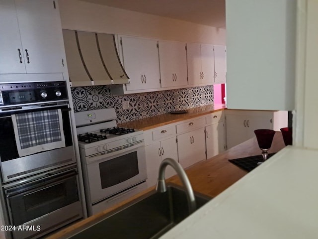 kitchen with light countertops, double oven, ventilation hood, and gas range gas stove