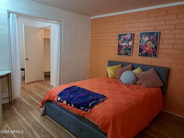 bedroom with brick wall and wood finished floors