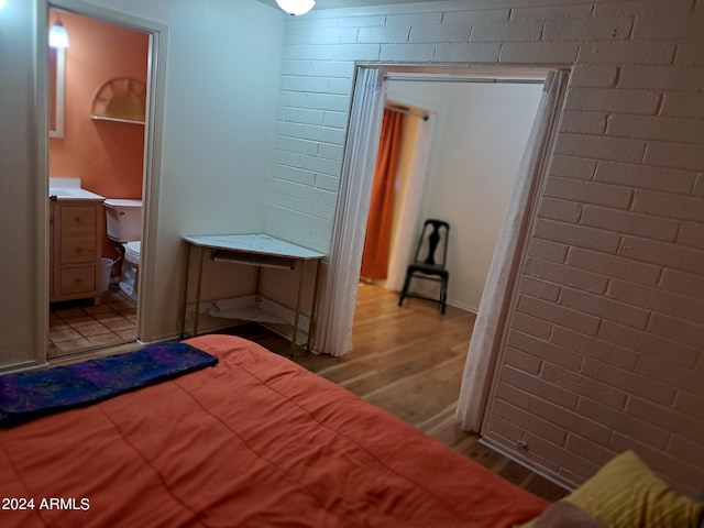 bedroom featuring brick wall and light wood-style flooring