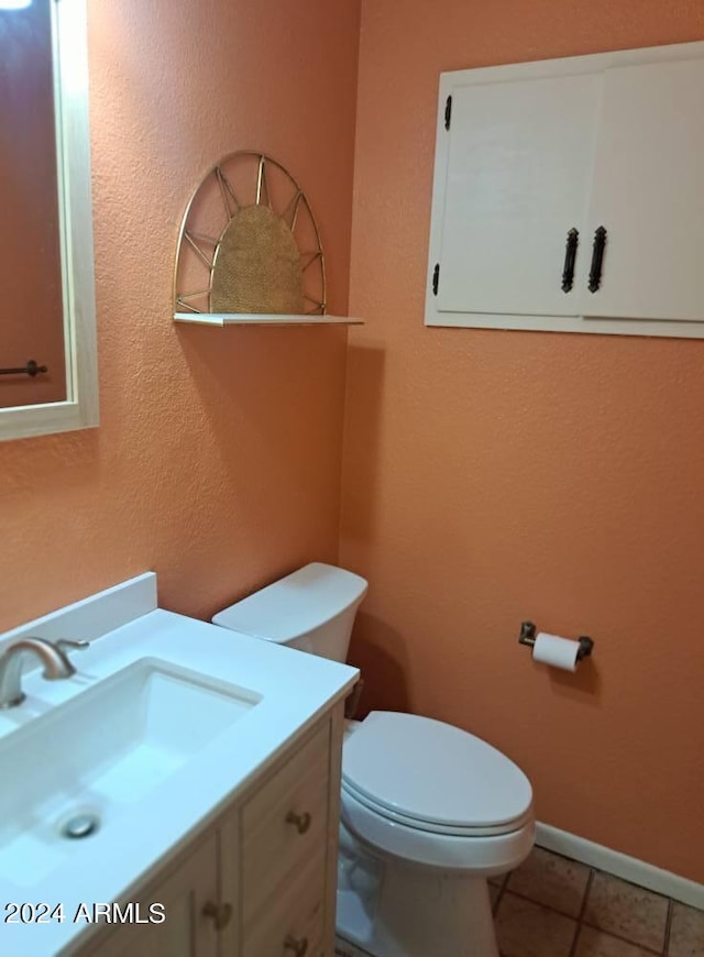 half bathroom featuring toilet, vanity, tile patterned floors, and baseboards