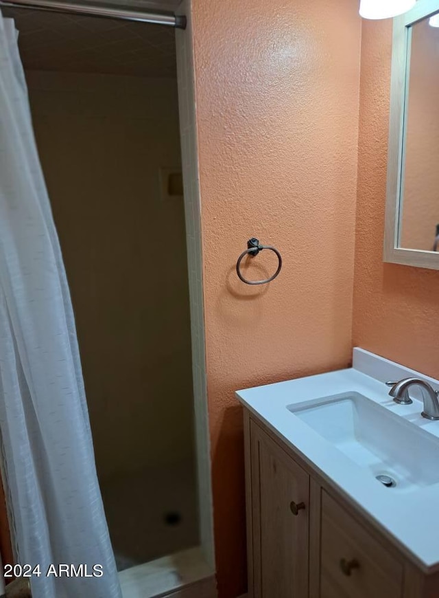 full bath featuring a textured wall, vanity, and a stall shower