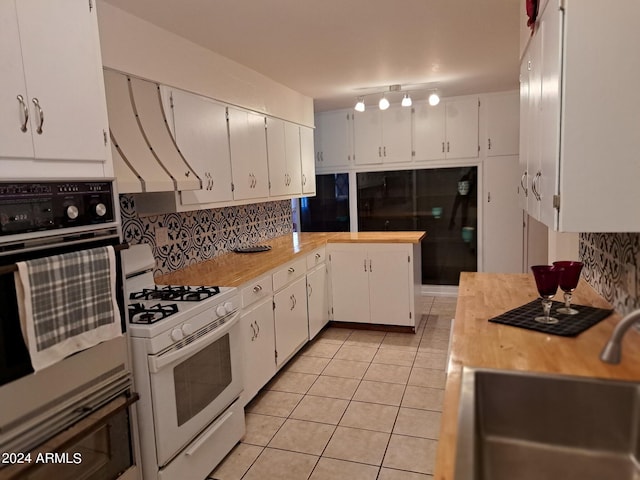 kitchen featuring a sink, decorative backsplash, white appliances, light countertops, and light tile patterned floors