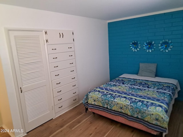 bedroom with brick wall and wood finished floors