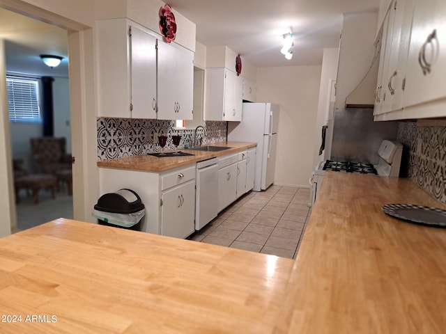 kitchen featuring white cabinets, backsplash, light tile patterned floors, a sink, and white appliances