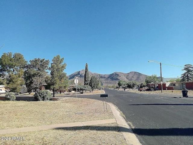 view of road featuring a mountain view, sidewalks, curbs, and street lighting