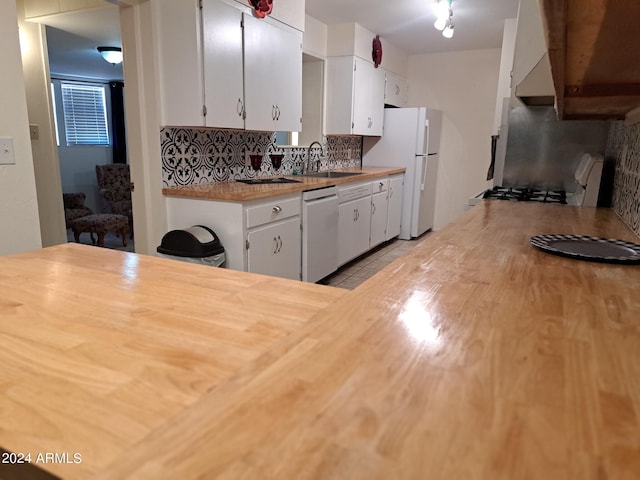 kitchen with white cabinets, a sink, tasteful backsplash, freestanding refrigerator, and dishwasher