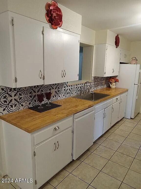 kitchen with white appliances, a sink, white cabinetry, and light tile patterned flooring