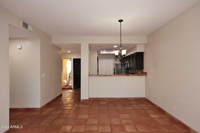 kitchen with baseboards, visible vents, appliances with stainless steel finishes, a peninsula, and a notable chandelier