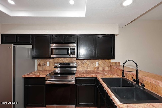 kitchen with light countertops, appliances with stainless steel finishes, backsplash, and a sink