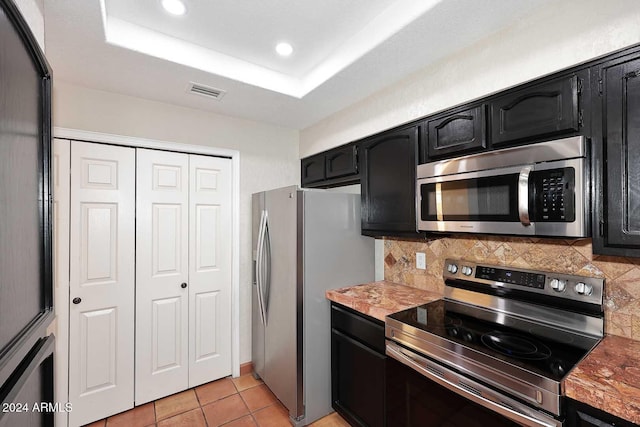 kitchen with visible vents, light countertops, appliances with stainless steel finishes, backsplash, and a tray ceiling