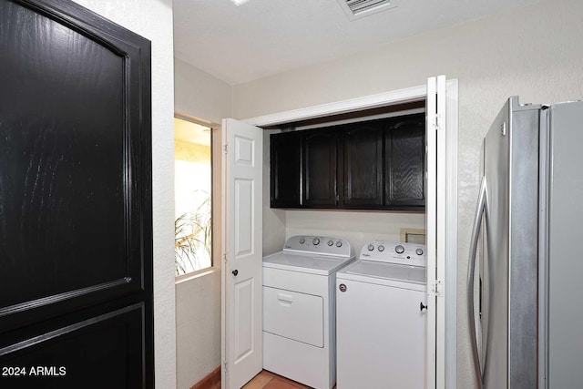 laundry area with a textured wall, cabinet space, independent washer and dryer, and visible vents